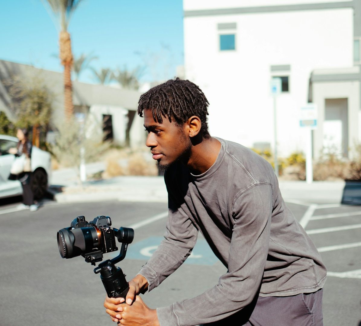 A content creator filming digital media in a parking lot during the day